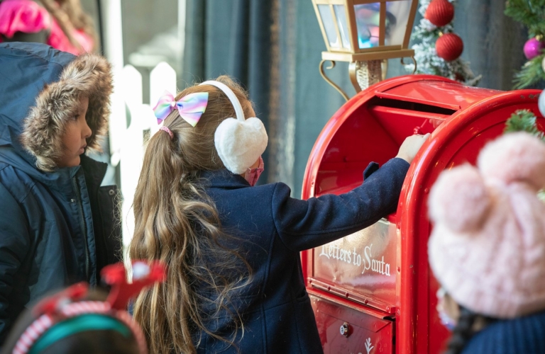 Girl putting letter to Santa in  mailbox
