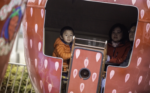 Family looks out from strawberry shaped Ferris wheel car